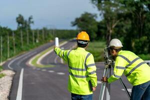 Zusammenarbeit von Landvermesser Ingenieure Arbeiter Herstellung Messung mit Theodolit auf Straße funktioniert. Umfrage Ingenieur beim Straße Konstruktion Grundstück, Landvermesser Ausrüstung. foto