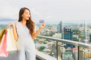 Porträt schöne junge asiatische Frau glücklich und Lächeln mit Kreditkarte für Einkaufstasche aus Kaufhaus foto