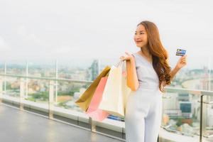 Porträt schöne junge asiatische Frau glücklich und Lächeln mit Kreditkarte für Einkaufstasche aus Kaufhaus foto