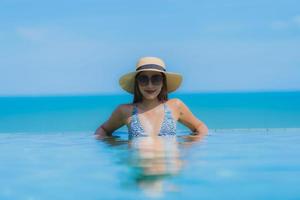 Porträt schöne junge asiatische Frau glückliches Lächeln entspannen Sie sich im Schwimmbad im Hotelresort in der Nähe des Meeresstrandes am blauen Himmel foto