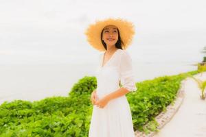 Porträt schöne asiatische Frau trägt Hut mit Lächeln glückliche Freizeit am Strand und Meer im Urlaub foto