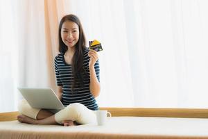 Porträt schöne junge asiatische Frau mit Computer-Notebook oder Laptop mit Kreditkarte zum Einkaufen foto