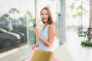 Porträt schöne junge asiatische Frau glücklich und Lächeln mit Einkaufstasche aus Kaufhaus foto