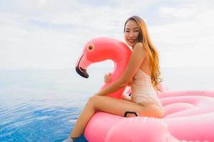 Porträt der jungen asiatischen Frau auf aufblasbarem Flamingo um den Außenpool im Hotelresort? foto