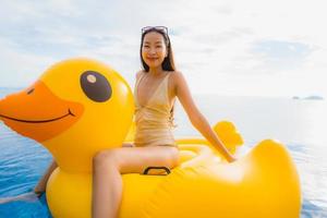 Porträt der jungen asiatischen Frau auf aufblasbarem Schwimmer gelbe Ente um den Außenpool im Hotel und Resort foto