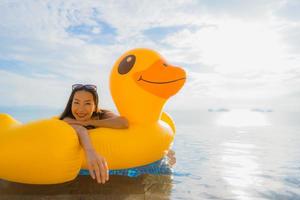 Porträt der jungen asiatischen Frau auf aufblasbarem Schwimmer gelbe Ente um den Außenpool im Hotel und Resort foto