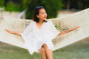 Porträt schöne junge asiatische Frau sitzt auf Hängematte am Meer Strand Ozean zum Entspannen foto