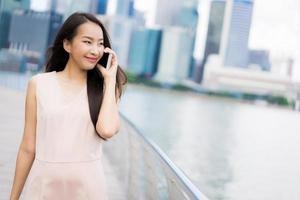 asiatische Frau, die Smartphone oder Handy zum Sprechen oder Text verwendet foto