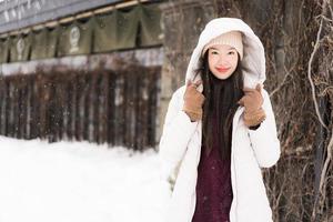 schöne junge asiatische frau, die glücklich für reisen in der schneewintersaison lächelt