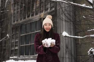 schöne junge asiatische frau, die glücklich für reisen in der schneewintersaison lächelt foto