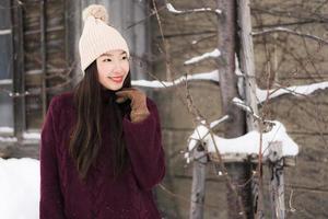 schöne junge asiatische frau, die glücklich für reisen in der schneewintersaison lächelt foto