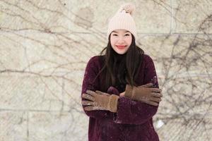 schöne junge asiatische frau, die glücklich für reisen in der schneewintersaison lächelt foto