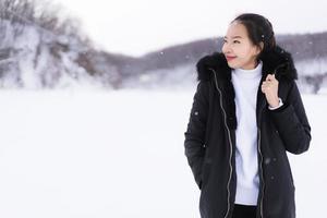 schöne junge asiatische frau, die glücklich für reisen in der schneewintersaison lächelt foto