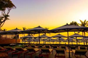 Sonnenschirme und Stühle rund um den Außenpool im Hotelresort für Urlaubsreisen im Hintergrund