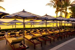 Sonnenschirme und Stühle rund um den Außenpool im Hotelresort für Urlaubsreisen im Hintergrund foto
