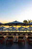 Sonnenschirme und Stühle rund um den Außenpool im Hotelresort für Urlaubsreisen im Hintergrund