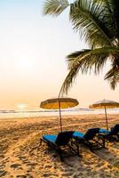 Sonnenschirm Strandkorb mit Palme und Meeresstrand bei Sonnenaufgang - Urlaubs- und Urlaubskonzept foto