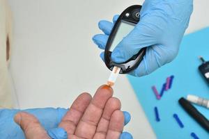 Arzt überprüft den Blutzuckerspiegel mit Glucometer foto