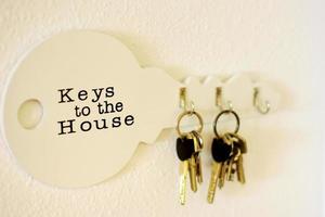 Schlüsselbund hängt an einem Halter an einer weißen Wand, Holzschlüsselhalter an einer hellen Wand foto