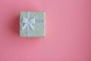 kleine Geschenkbox mit Schleife auf rosa Hintergrund