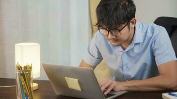 asiatisch Mann lächelnd Arbeiten online mit Laptop beim Zuhause Büro, Telearbeit Konzept. foto