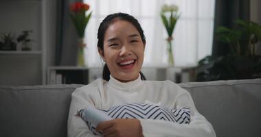 glücklich jung asiatisch Frau Aufpassen ein Film auf Fernsehen während Sitzung auf das Sofa foto