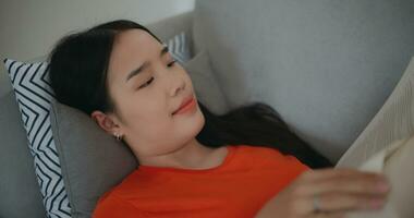 asiatisch Frau lesen ein Buch während Lügen auf das Sofa foto
