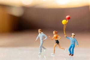 Miniaturmenschen, glückliche Familie, die mit Ballon läuft und spielt foto