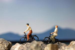 Miniaturmenschenreisender mit Fahrradfahren auf dem Felsen foto