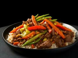 ein Teller von Chinesisch Reis mit ein Stapel von Chinesisch Rindfleisch und Gemüse auf oben auf schwarz Hintergrund foto
