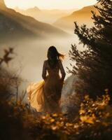 schön Frau im ein lange Gelb Kleid im das Berge beim Sonnenuntergang foto