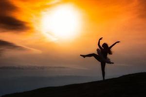 Ballerina Silhouette, tanzend allein in der Natur in den Bergen bei Sonnenuntergang foto