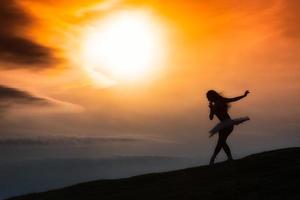 Ballerina Silhouette, tanzend allein in der Natur in den Bergen bei Sonnenuntergang foto