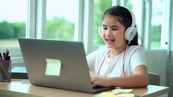 jung Mädchen mit Laptop beim heim. süß Schule lesen auf Computer Bildschirm Sitzung im Leben Zimmer. Kind spielen Spiel auf Laptop oder tun Hausaufgaben foto