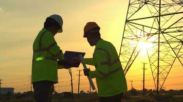 Silhouette von Ingenieur Teams suchen diskutieren planen. zwei Ingenieur Stehen auf Feld mit Elektrizität Türme beim Sonnenuntergang. foto