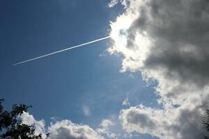 ein Regen Wolke im das Blau Himmel Das versteckte das Sonne. ein Strahl von ein Gewitterwolke, ein Weg von ein Flugzeug Über das Spitzen von Bäume - - ein horizontal Foto Nahaufnahme, Aussicht von unten