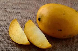 Mangofrucht mit Scheibe auf Sackleinenhintergrund foto