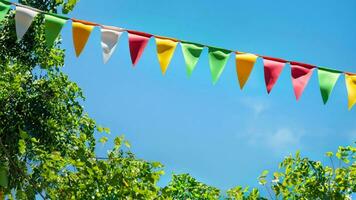 bunt Wimpel Zeichenfolge Dekoration im Grün Baum Laub auf Blau Himmel, Sommer- Party Hintergrund foto