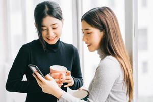 zwei asiatische geschäftsfrauen plauderten in der pause am fenster foto