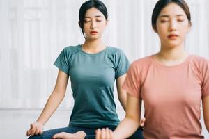 zwei asiatische frauen praktizieren zu hause meditation foto
