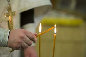 das Hände von das Priester Licht Kerzen foto