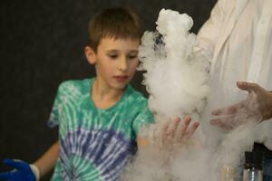 das Junge führt ein wissenschaftlich chemisch Experiment mit Flüssigkeit Stickstoff. foto