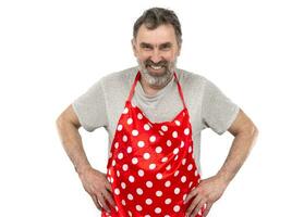 ein Alten bärtig Mann im ein rot Tupfen kulinarisch Schürze auf ein Weiß Hintergrund. foto