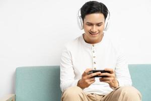 asiatischer Geschäftsmann, der drahtlose Kopfhörer trägt und Spiele auf seinem Telefon spielt foto
