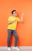 Ganzkörperfoto eines asiatischen Mannes im gelben Hemd auf orangem Hintergrund foto