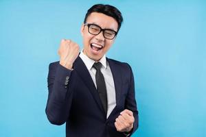 Porträt eines aufgeregten asiatischen Geschäftsmannes auf blauem Hintergrund foto