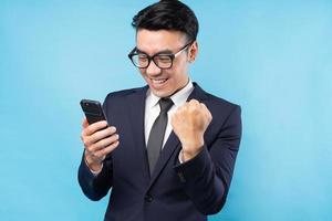 Asiatischer Geschäftsmann im Anzug mit Smartphone und Sieg fühlen foto