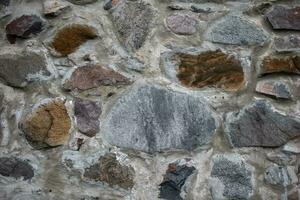 ein uralt Stein Mauer bestehend aus von Steine von anders Formen und Komposition. foto