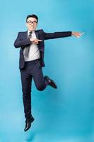 asiatischer Geschäftsmann im Anzug und auf blauem Hintergrund springen foto