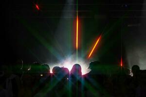 dunkel Silhouetten von Tanzen Menschen und ein Strahl von Licht im ein Nachtclub. foto